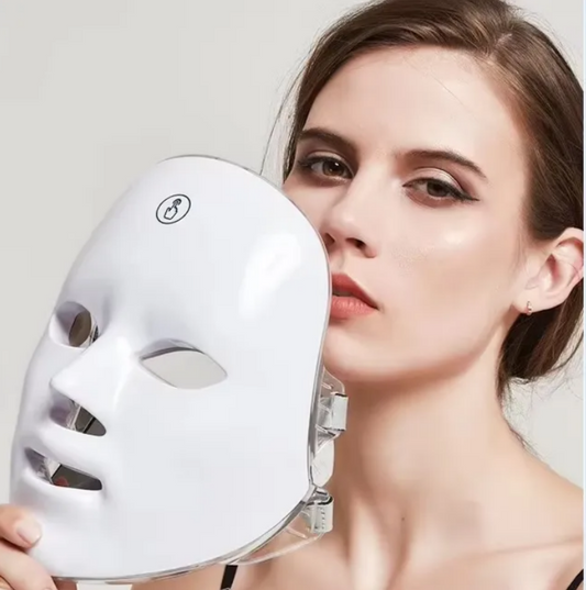 Woman holding a white LED face mask against a neutral background
